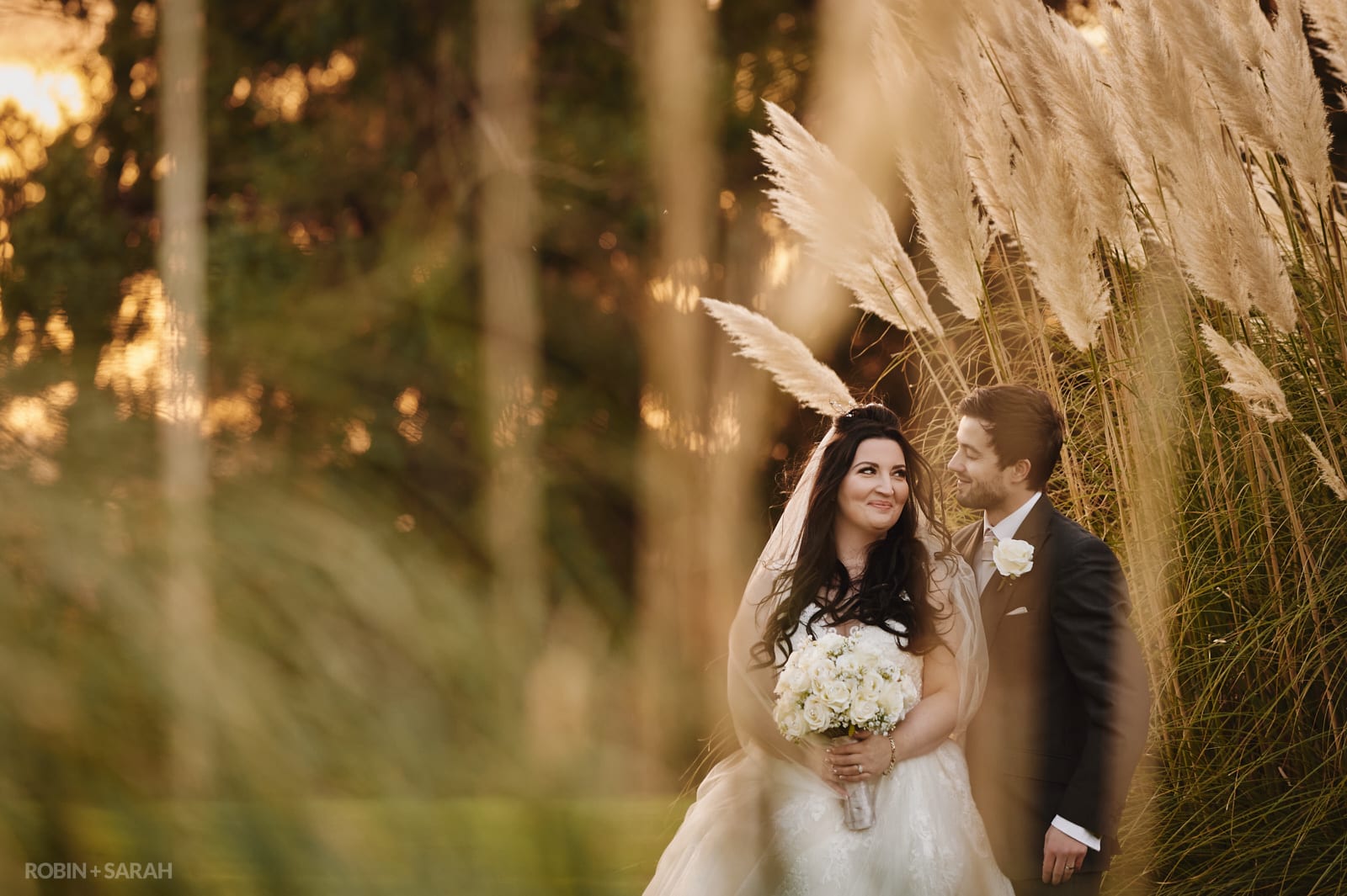 Bride and groom outside on a winter's afternoon surrounded by Pampas grass