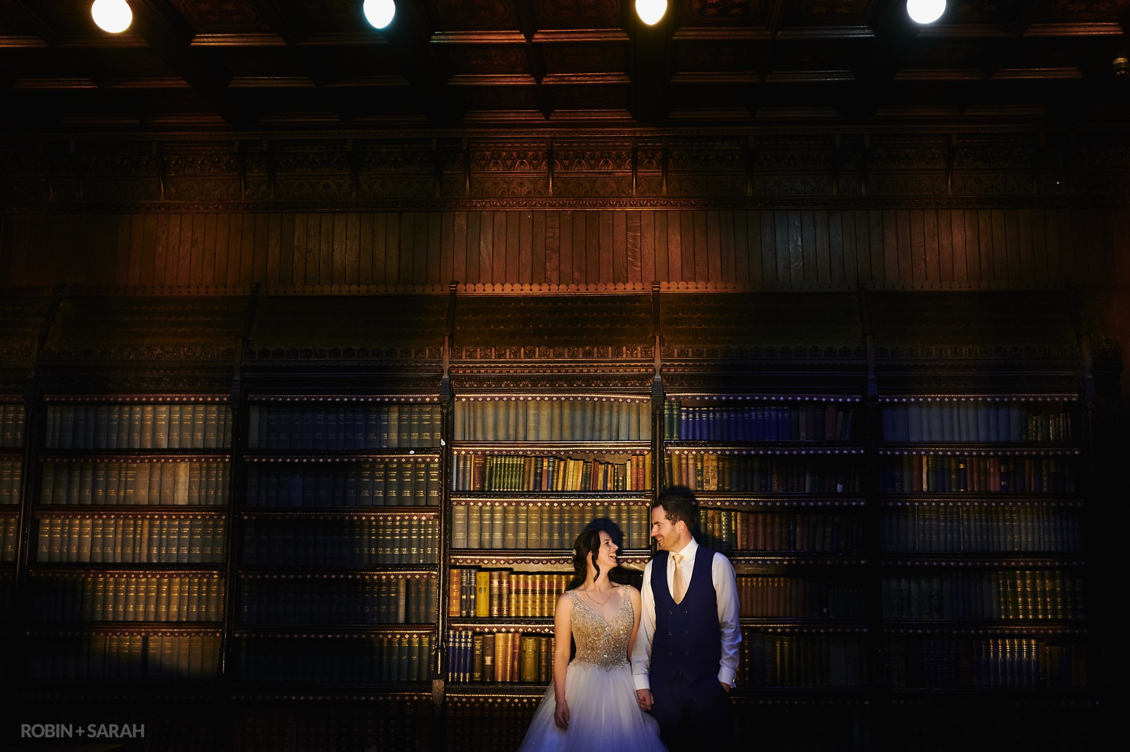 Bride and groom in library room at night, with eerie lighting
