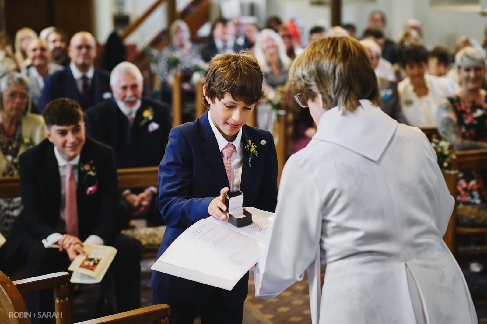 Page boy gives wedding rings to vicar during church ceremony