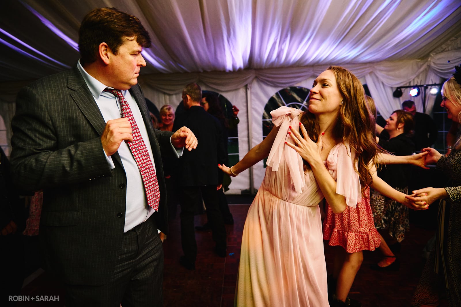Wedding guests dance in marquee reception