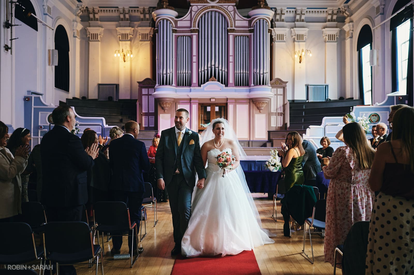 Bride and groom walk up aisle after getting married at Kidderminster Town Hall, as guests clap and cheer