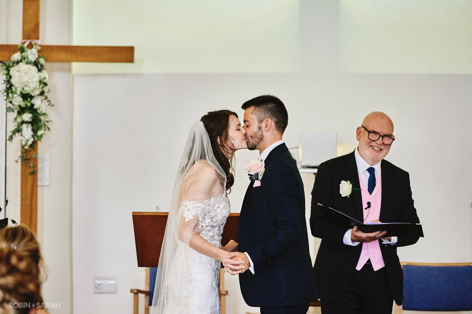 Bride and groom kiss during wedding ceremony at Long Buckby Baptist Church