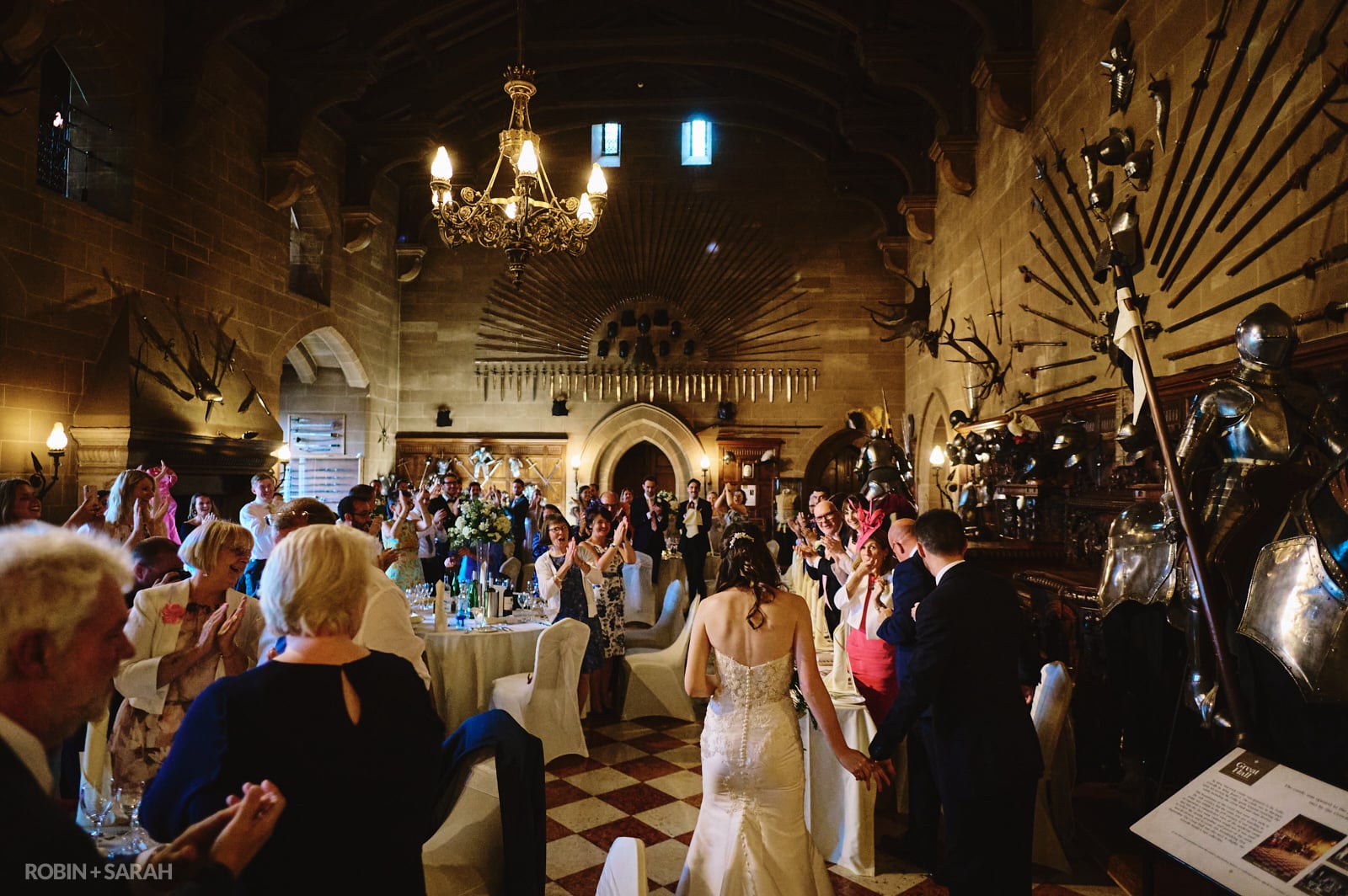 Bride and groom enter Great Hall at Warwick Castle as guests clap and cheer
