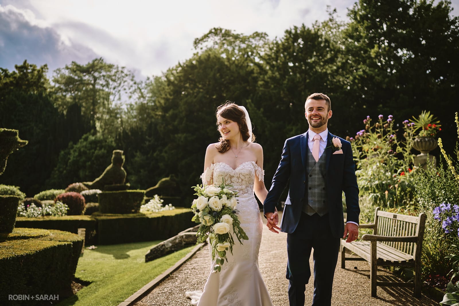 Bride and groom walking together in beautiful gardens