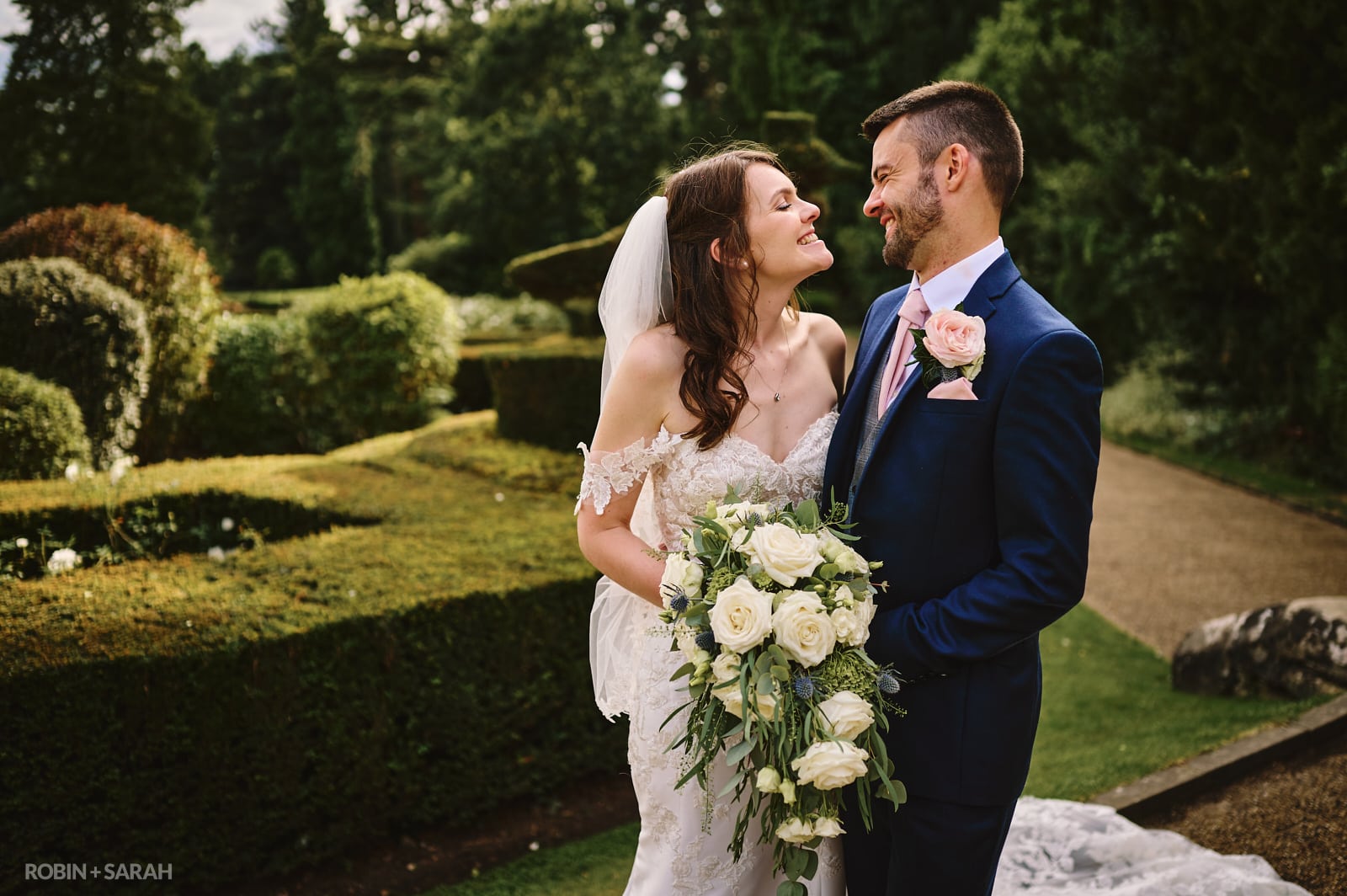 Bride and groom laughing together in topiary garden
