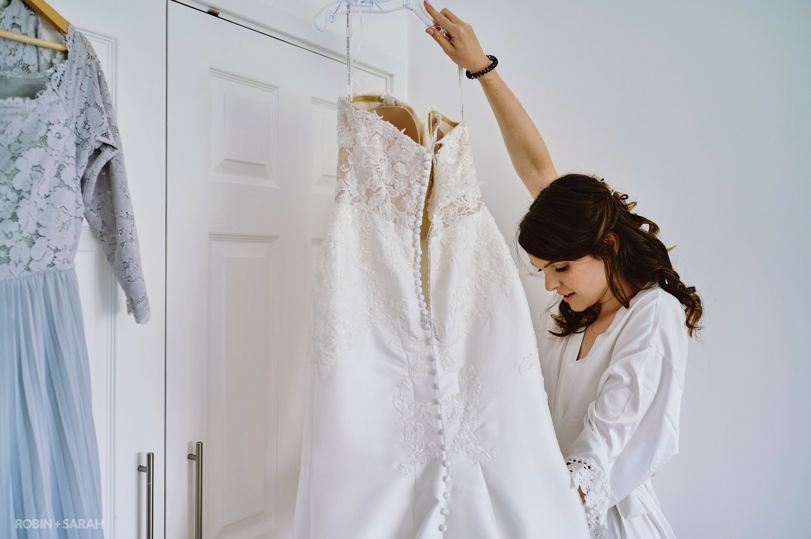 Bride holds up dress as she prepares for wedding day