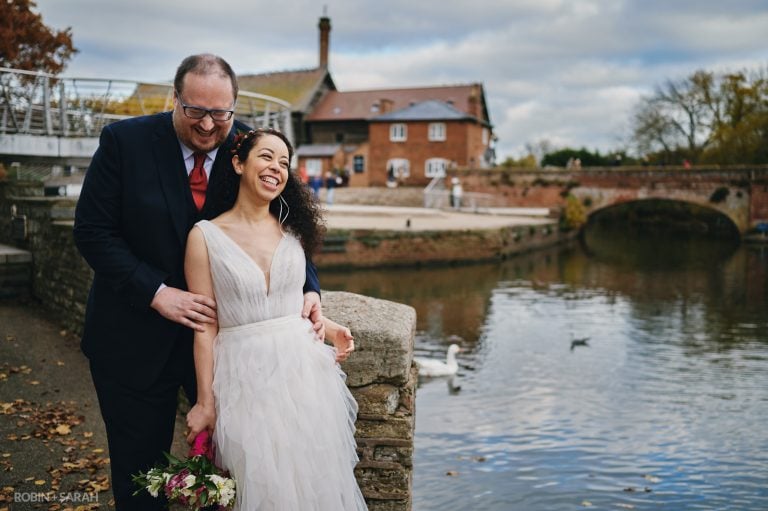 Bride and groom laughing together next to the River Avon in Stratford-upon-Avon