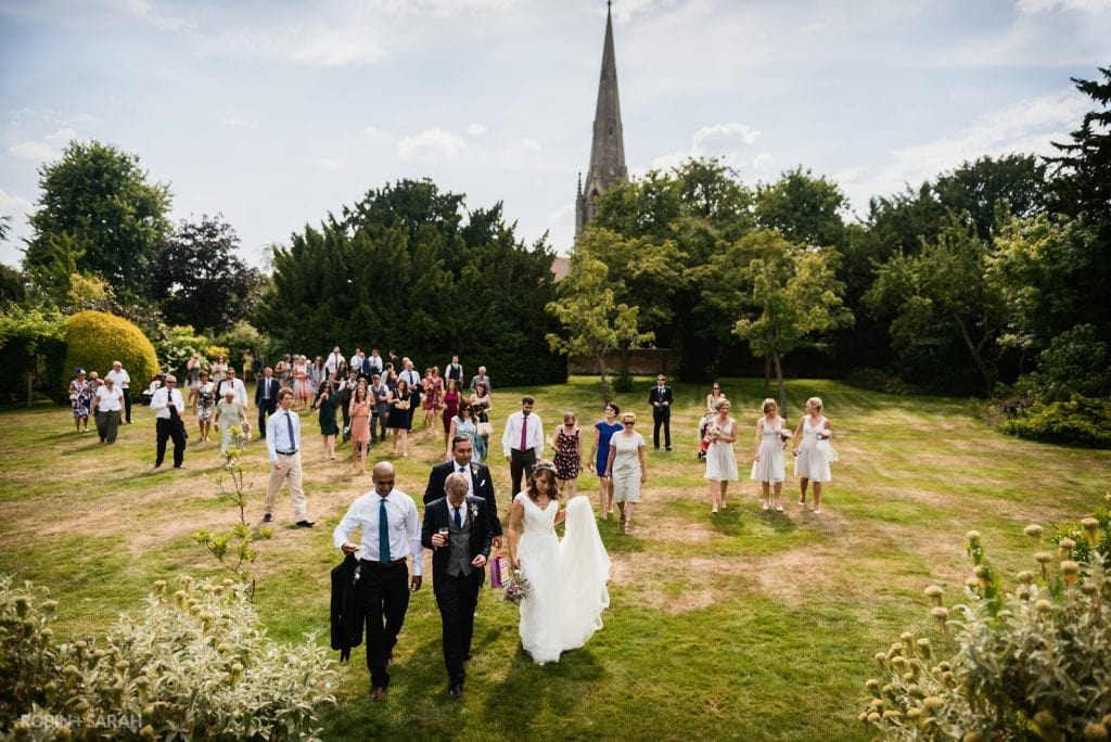 Bride, groom and wedding party walk across field