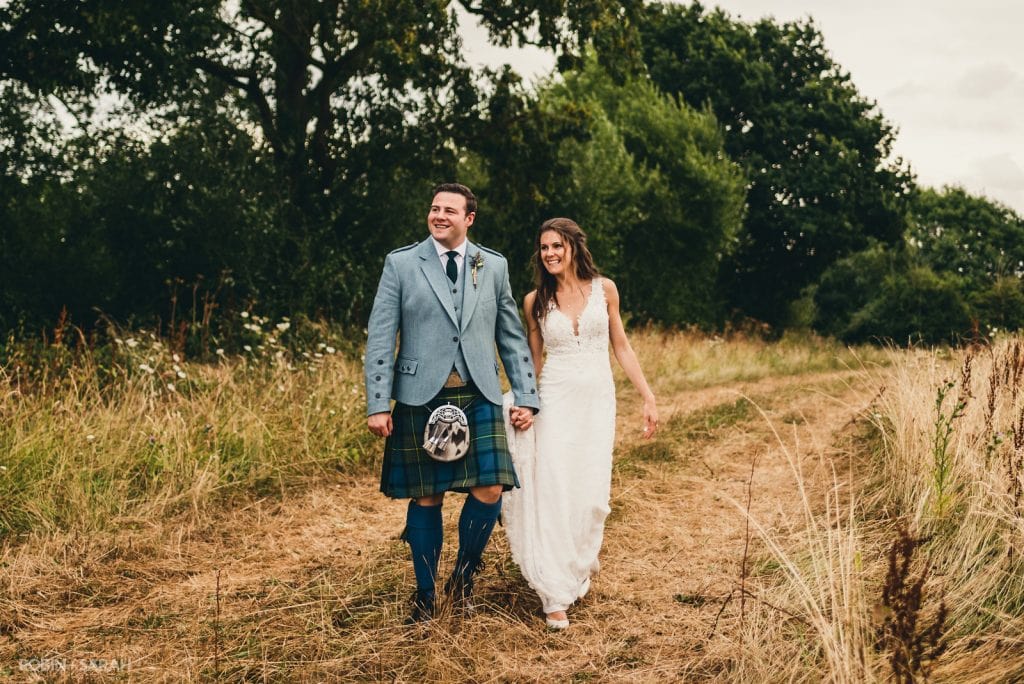 Bride and groom walk through fields