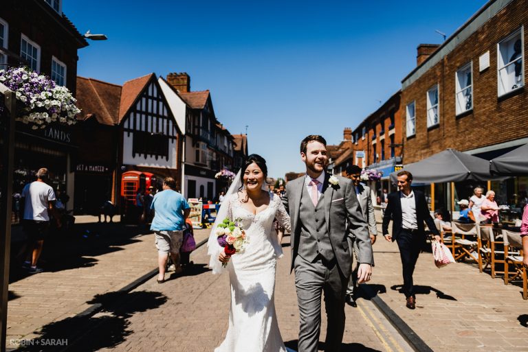 Bride and groom walk through Stratford-upon-Avon in Warwickshire after getting married