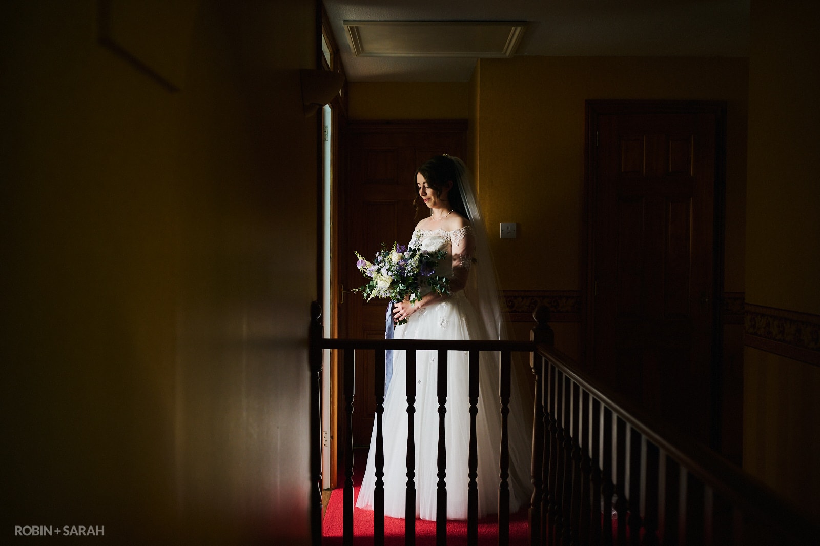 Bride ready for wedding standing in dark hallway with strong directional light