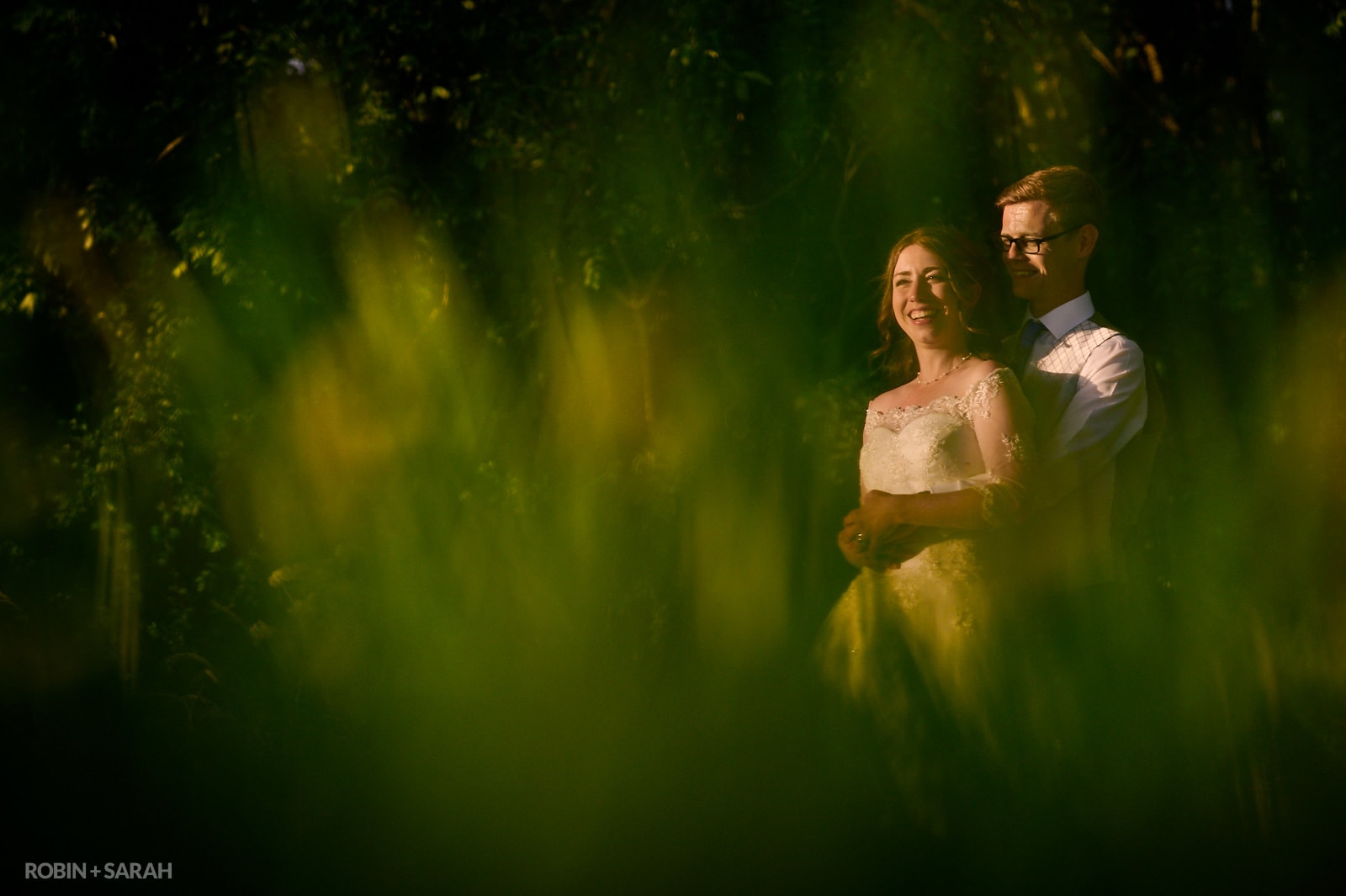 Bride and groom in field surrounded by long grass
