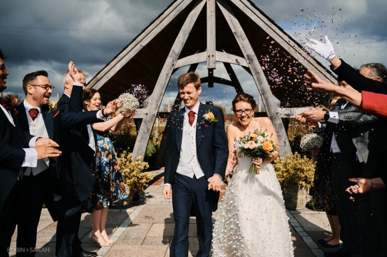 Bride and groom walk as guests throw confetti