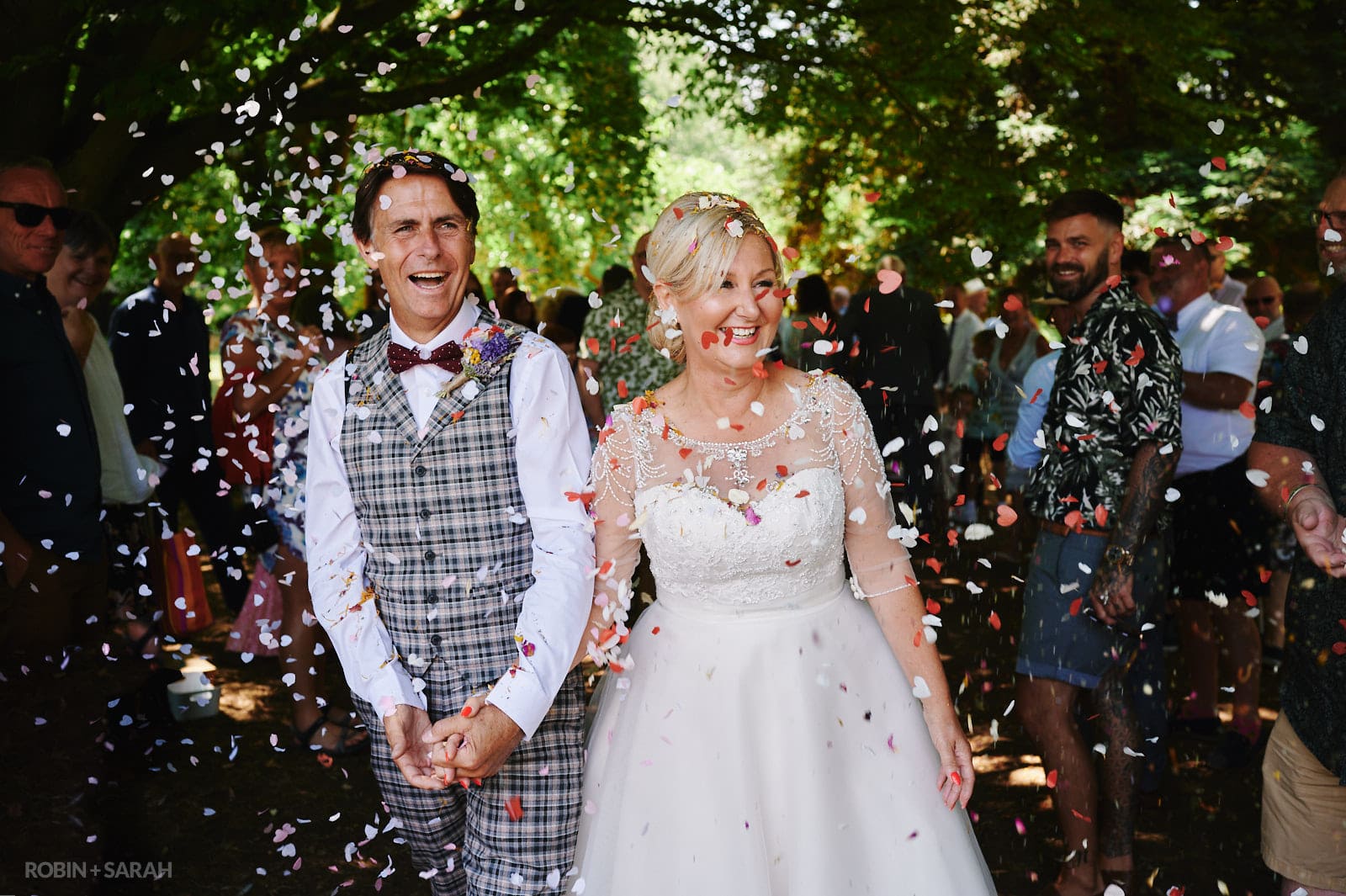 Bride and groom walk through confetti throw during outdoor wedding ceremony at Oakfield Gardens