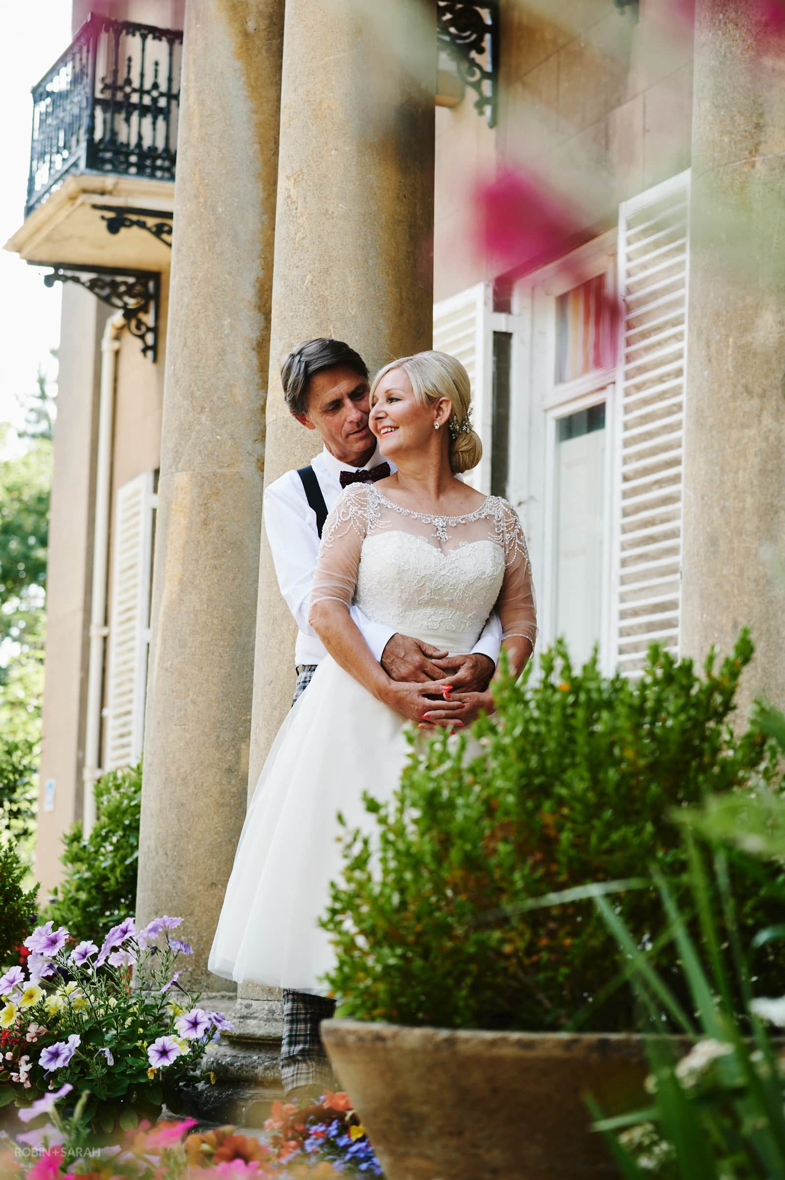 Bride and groom between roman columns at Oakfield Gardens wedding venue