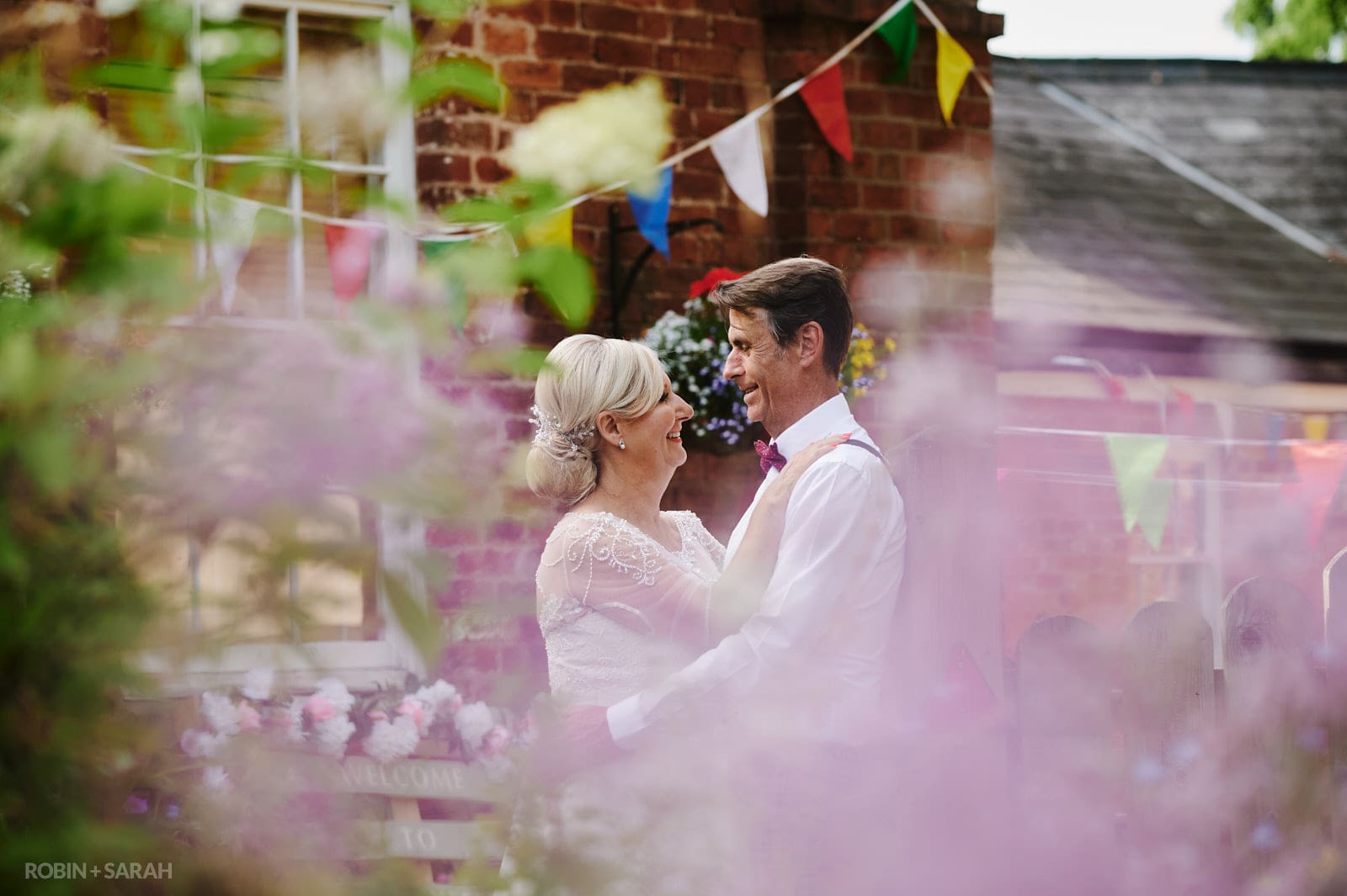 Bride and groom at Oakfield Gardens with bunting draped across buildings
