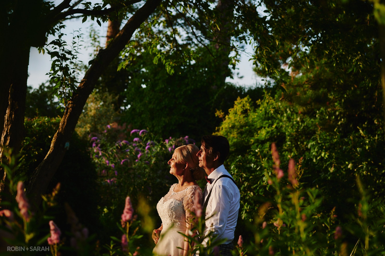 Bride and groom in beautiful gardens with evening light highlighting their faces