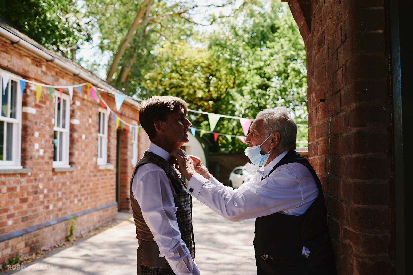 Groom has bow tie fixed by elderly wedding guest