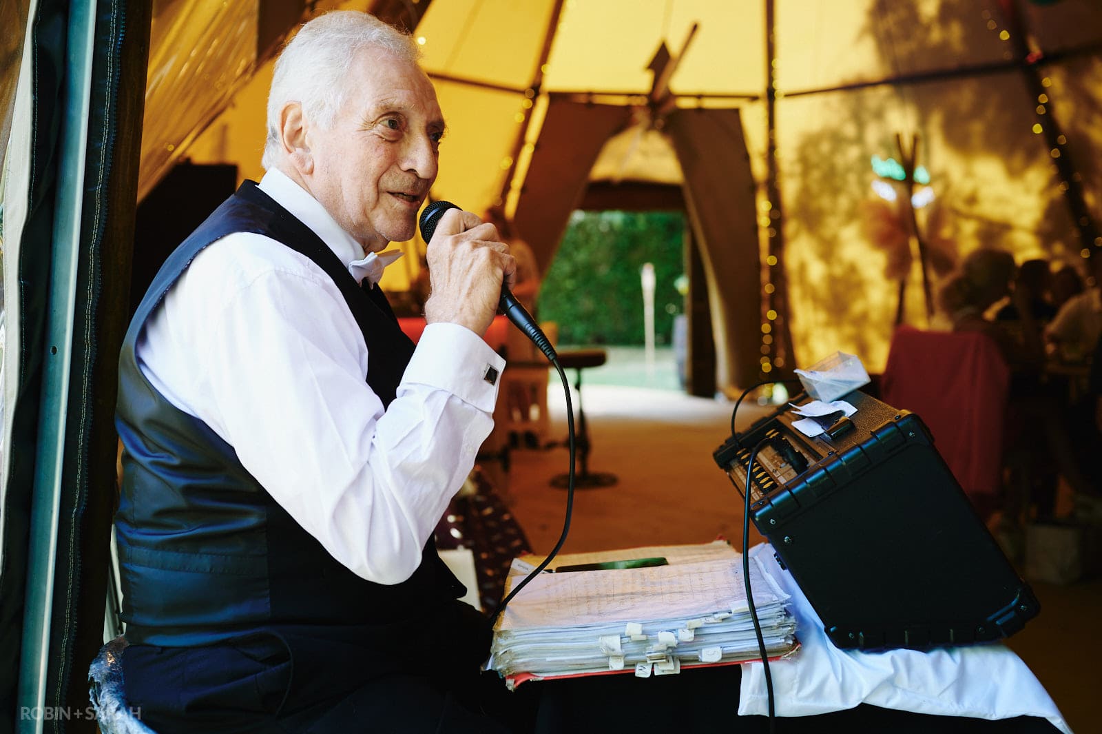 Elderly singer performs for wedding guests inside tipi