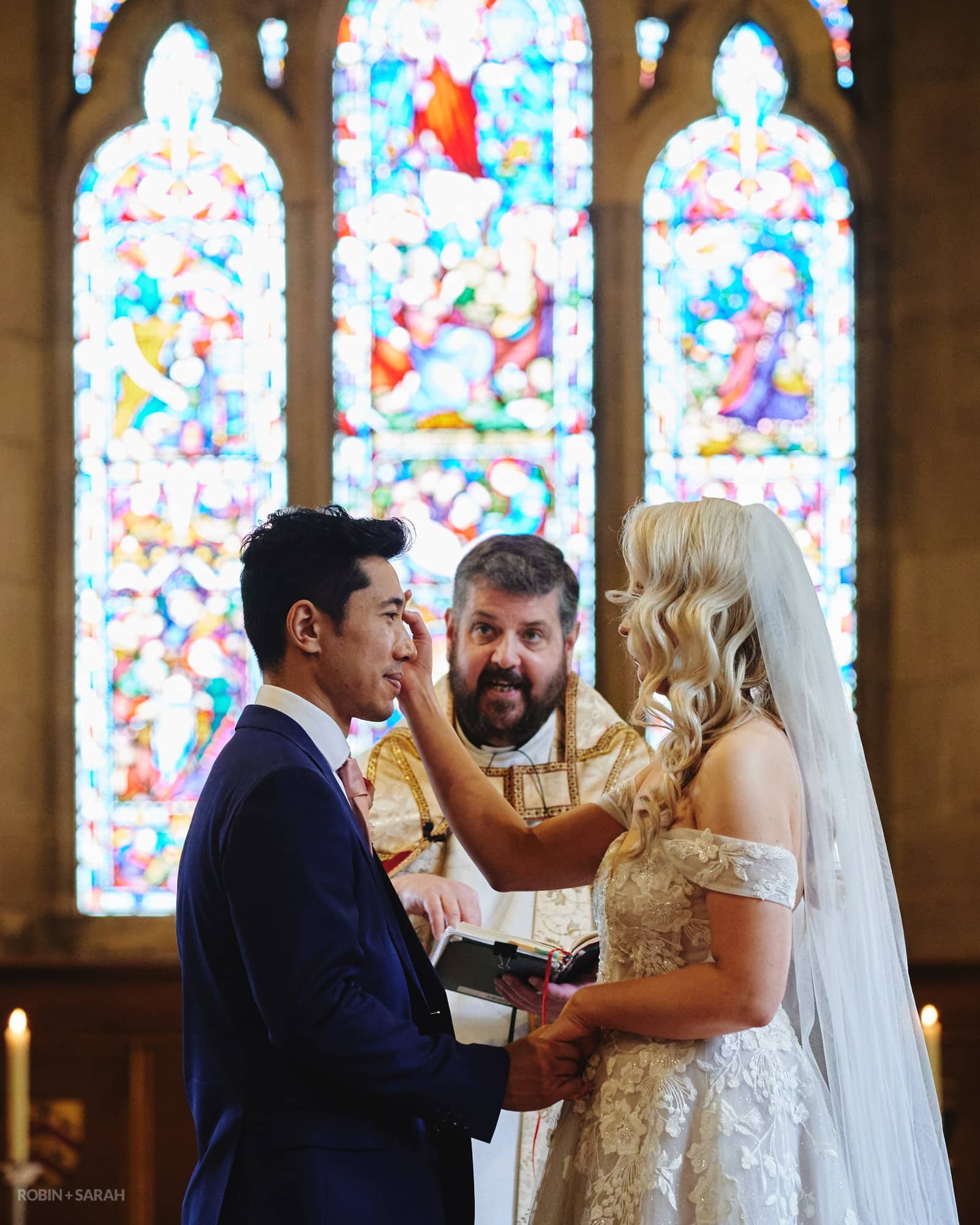 Bride touches groom's head during wedding ceremony at Feckenham Church