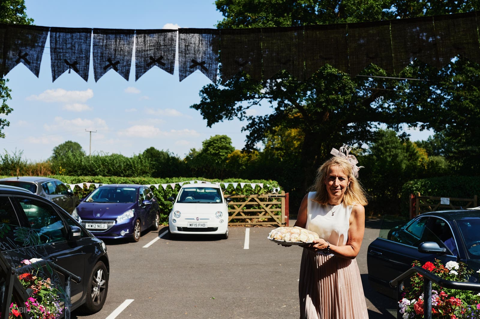Wedding guest arrives at Bentley Village Hall with plate of handmake cakes