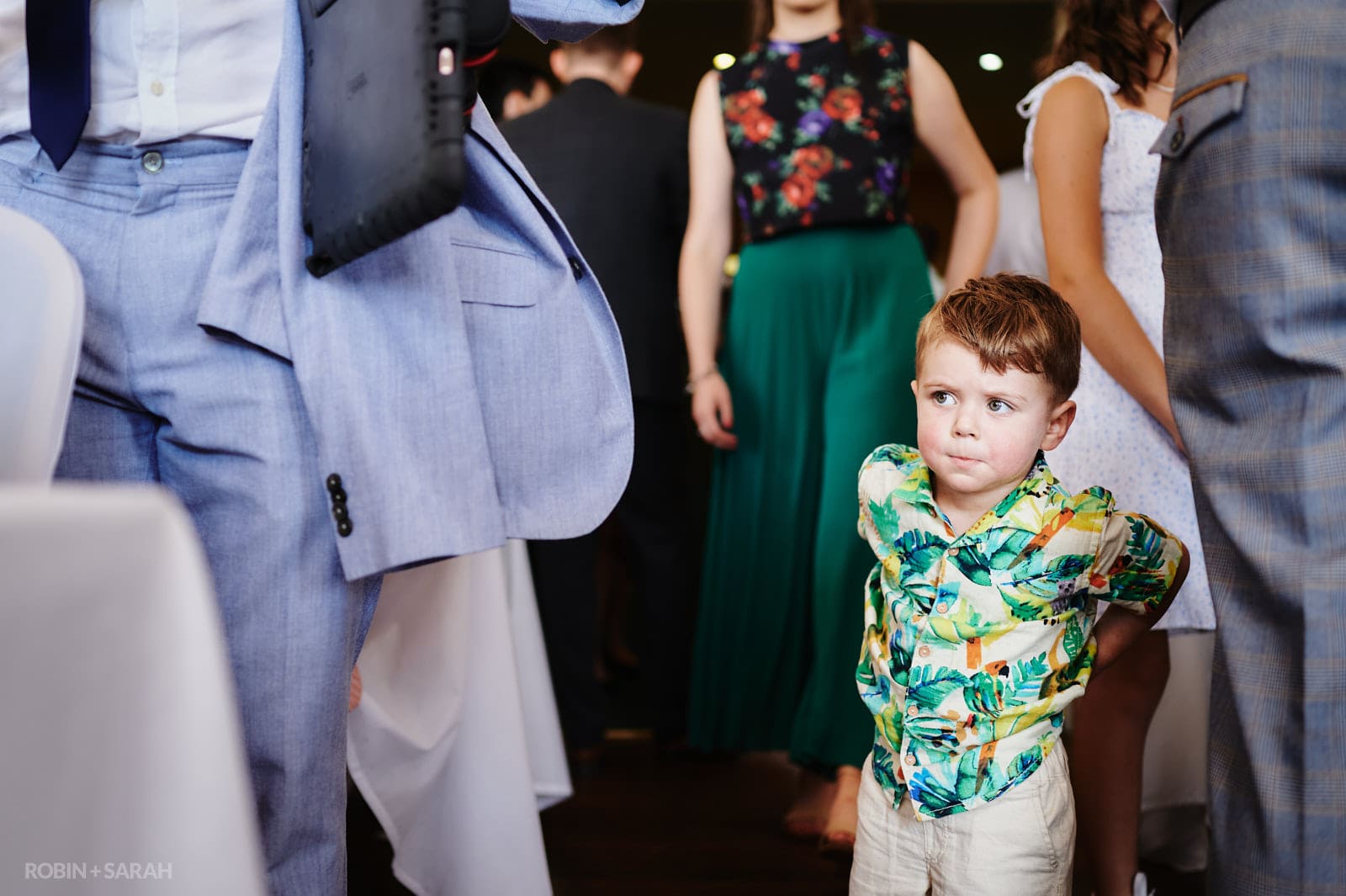 Boy peeks between wedding guests
