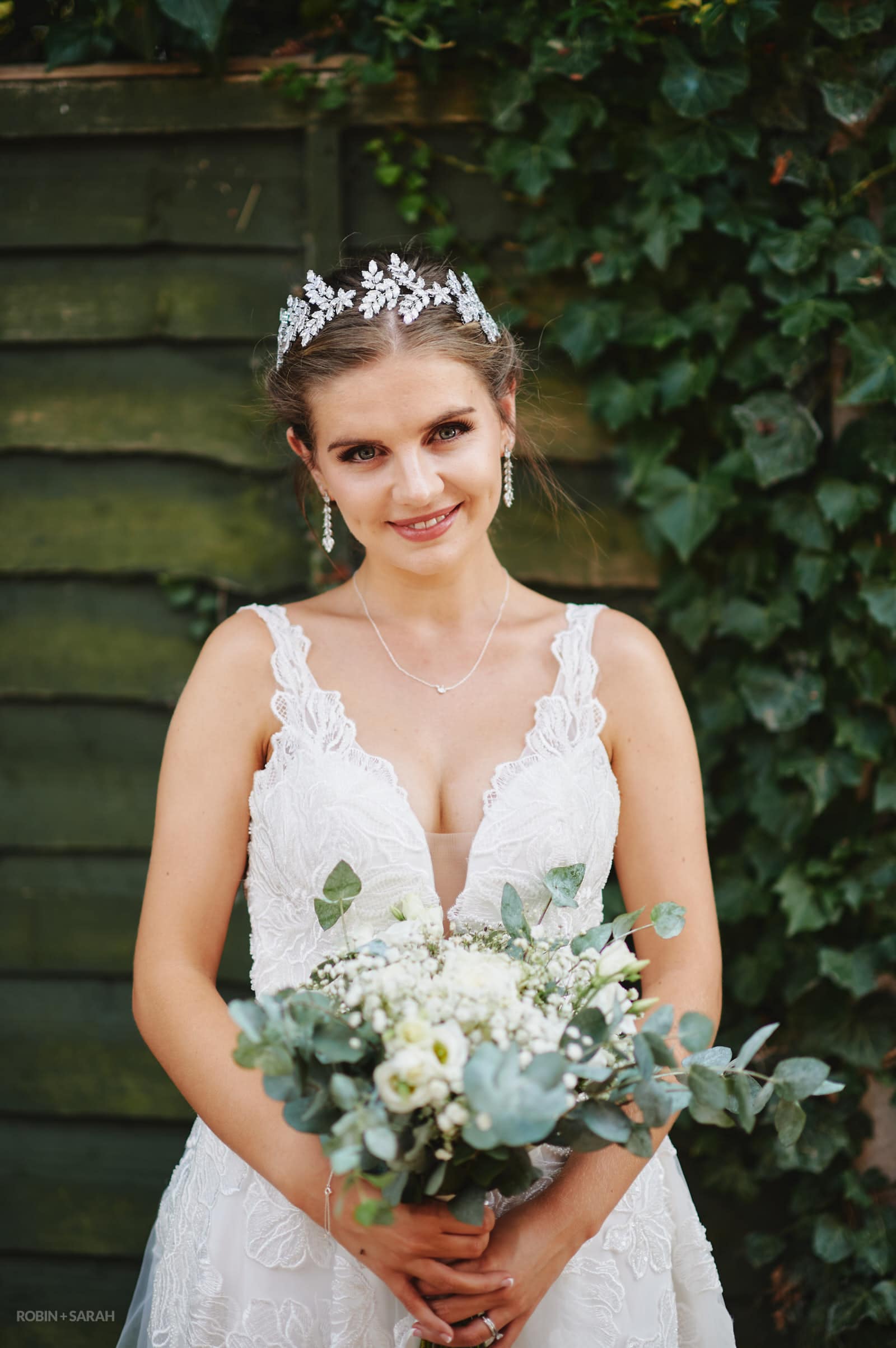 Portrait of bride in beautiful white wedding dress holding bouquet and wearing leaf tiara