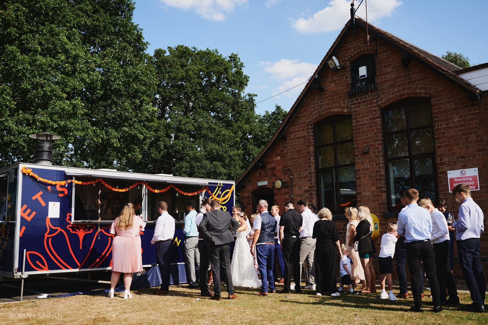 Wedding guests queue for food from mobile catering van at Wedding speeches at Bentley Village Hall