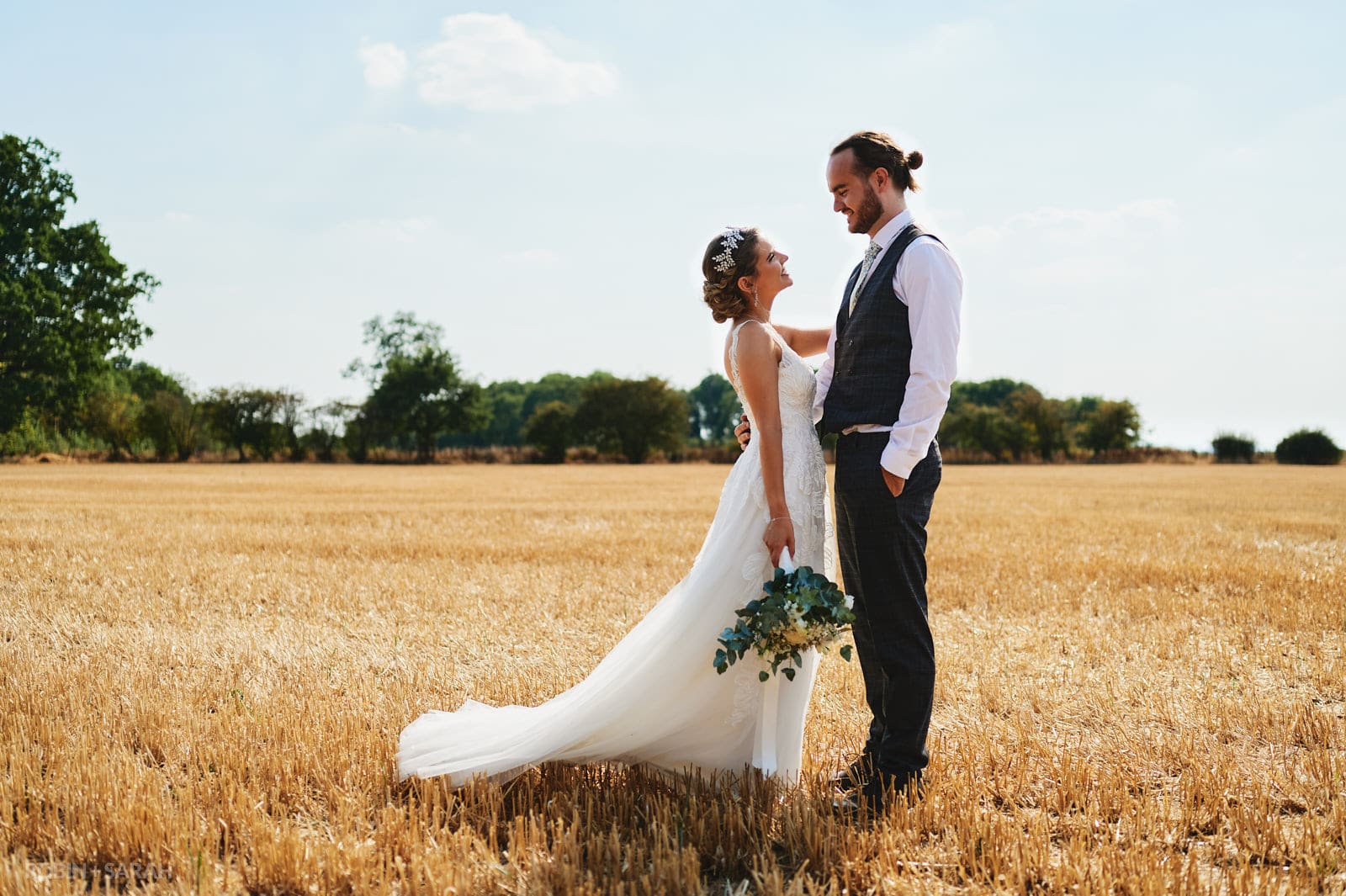 Bride and groom in field on bright sunny day