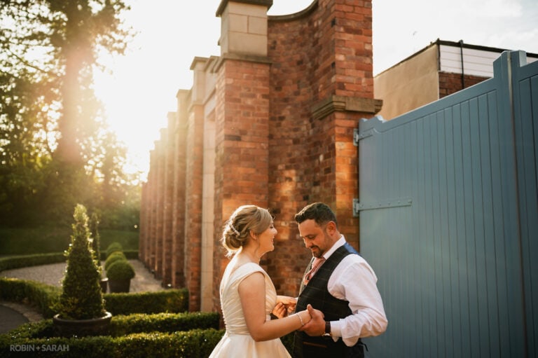 Bride and groom outside in beautiful sunset light next to large blue gate