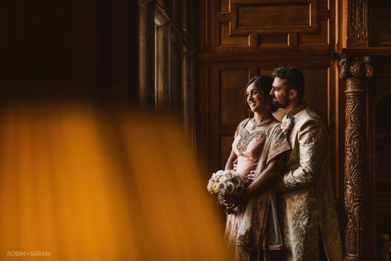 Bride and groom in Indian wedding outfits in beautiful wood panelled room at Pendrell Hall