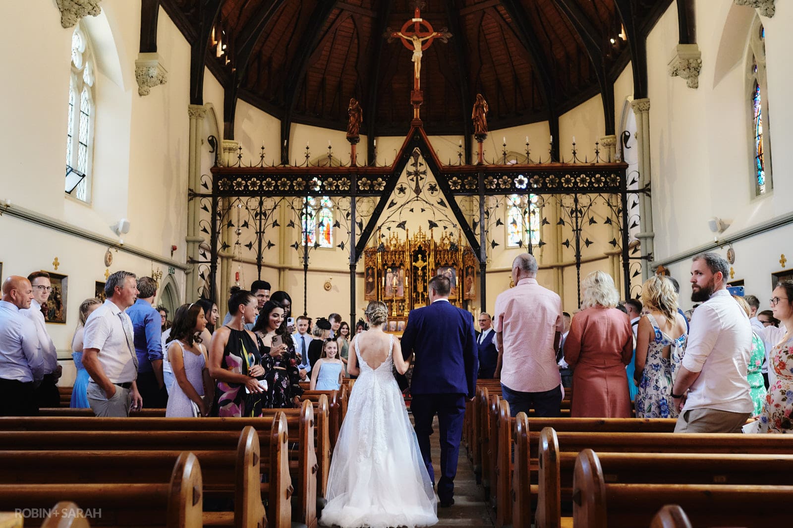 Bride and father walk up aisle at St Peter's church Bromsgrove as guests watch
