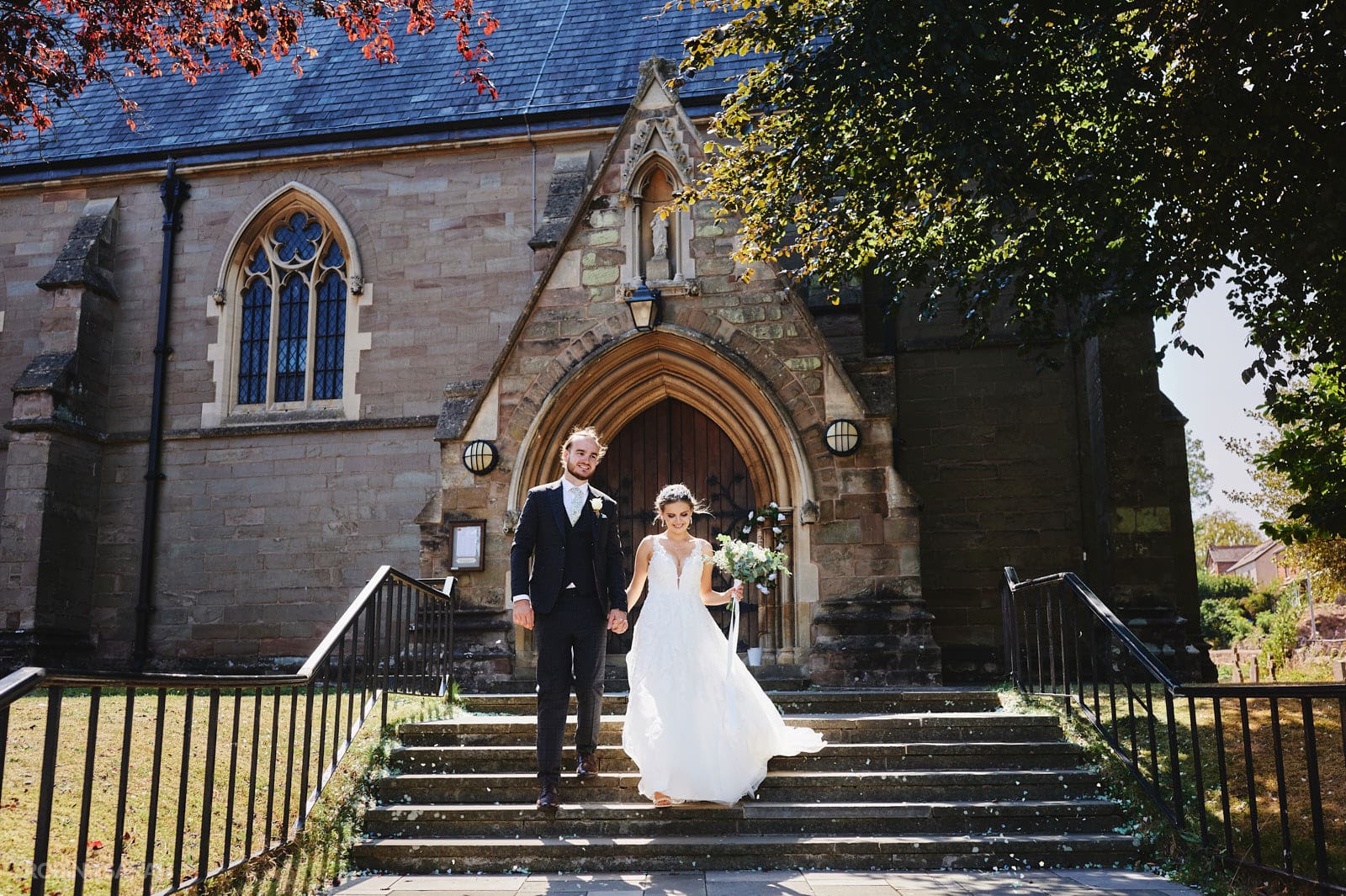 Bride and groom walk down steps at St Peter's church Bromsgrove