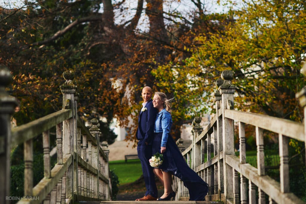 Bride and groom relax together on beautiful wooden bridge in Priory Park Malvern