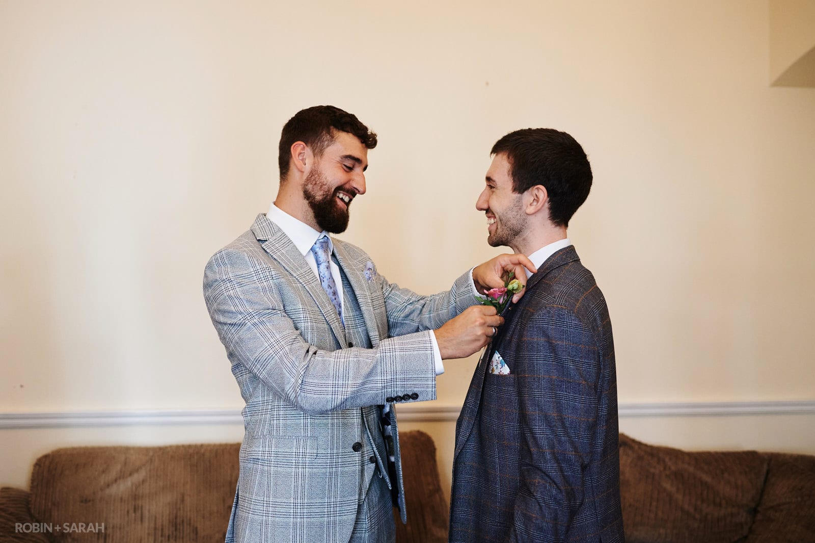 Groomsmen pins buttonhole flower onto groom's suit