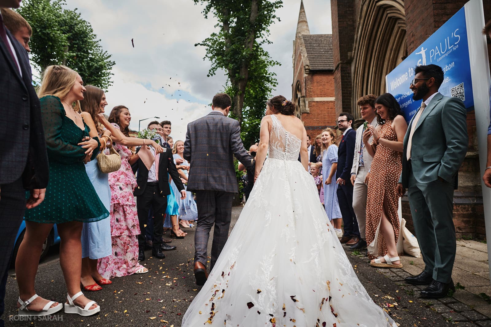 Bride and groom have confetti thrown over them by wedding guests