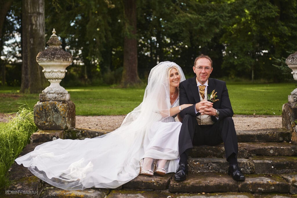 Bride and groom relaxed and sitting on steps in gardens at Staunton Harold