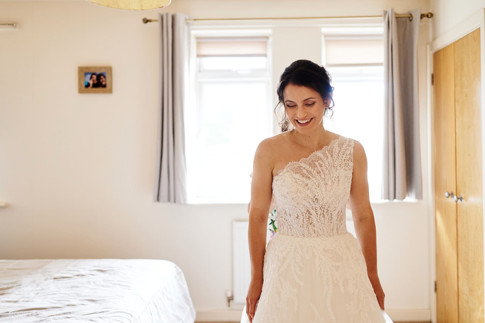 Bride smiling as her wedding dress is fastened