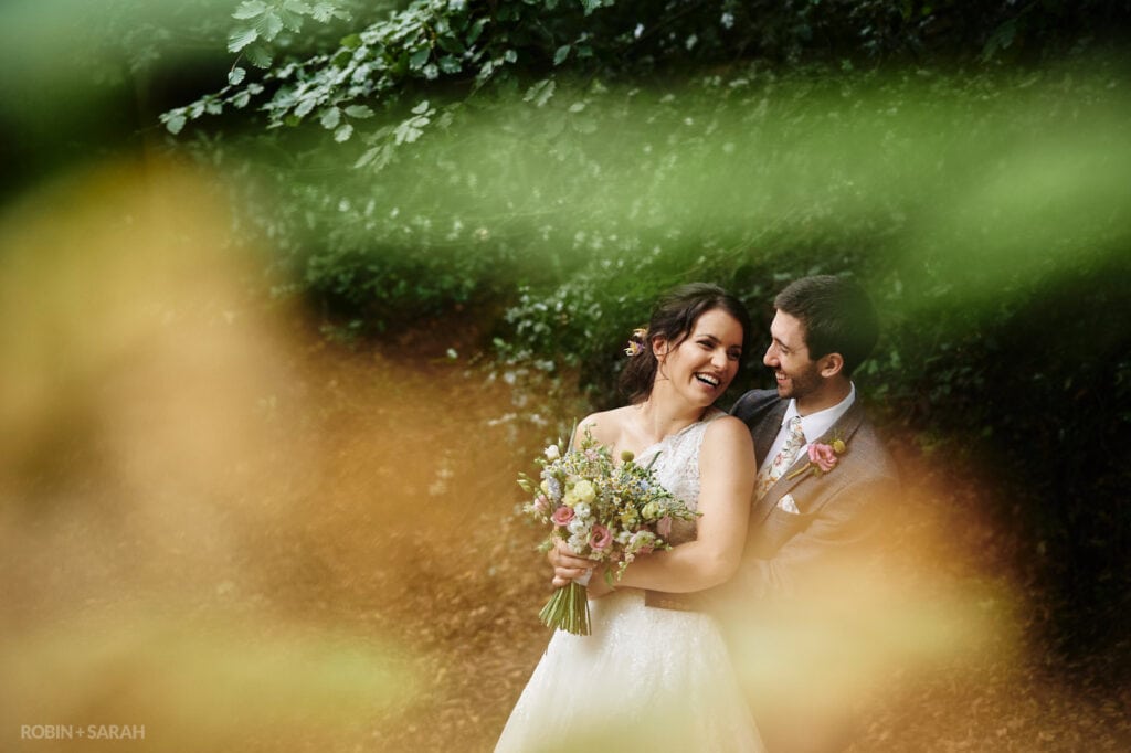 Bride and groom laughing together in woods
