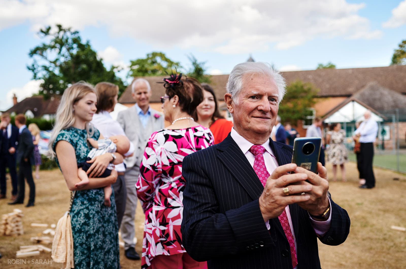 Wedding guest takes photo on his phone at village hall wedding