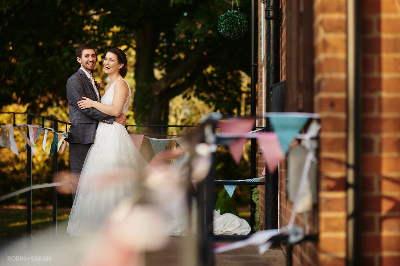 Bride and groom laughing together outside Dorothea Mitchell village hall in Warwickshire