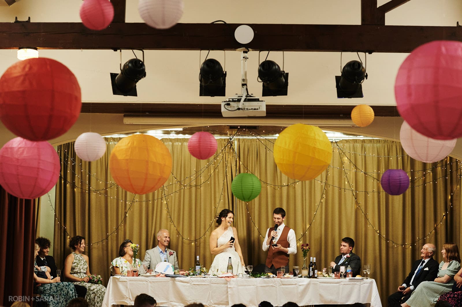 Bride and groom give wedding speech in village hall