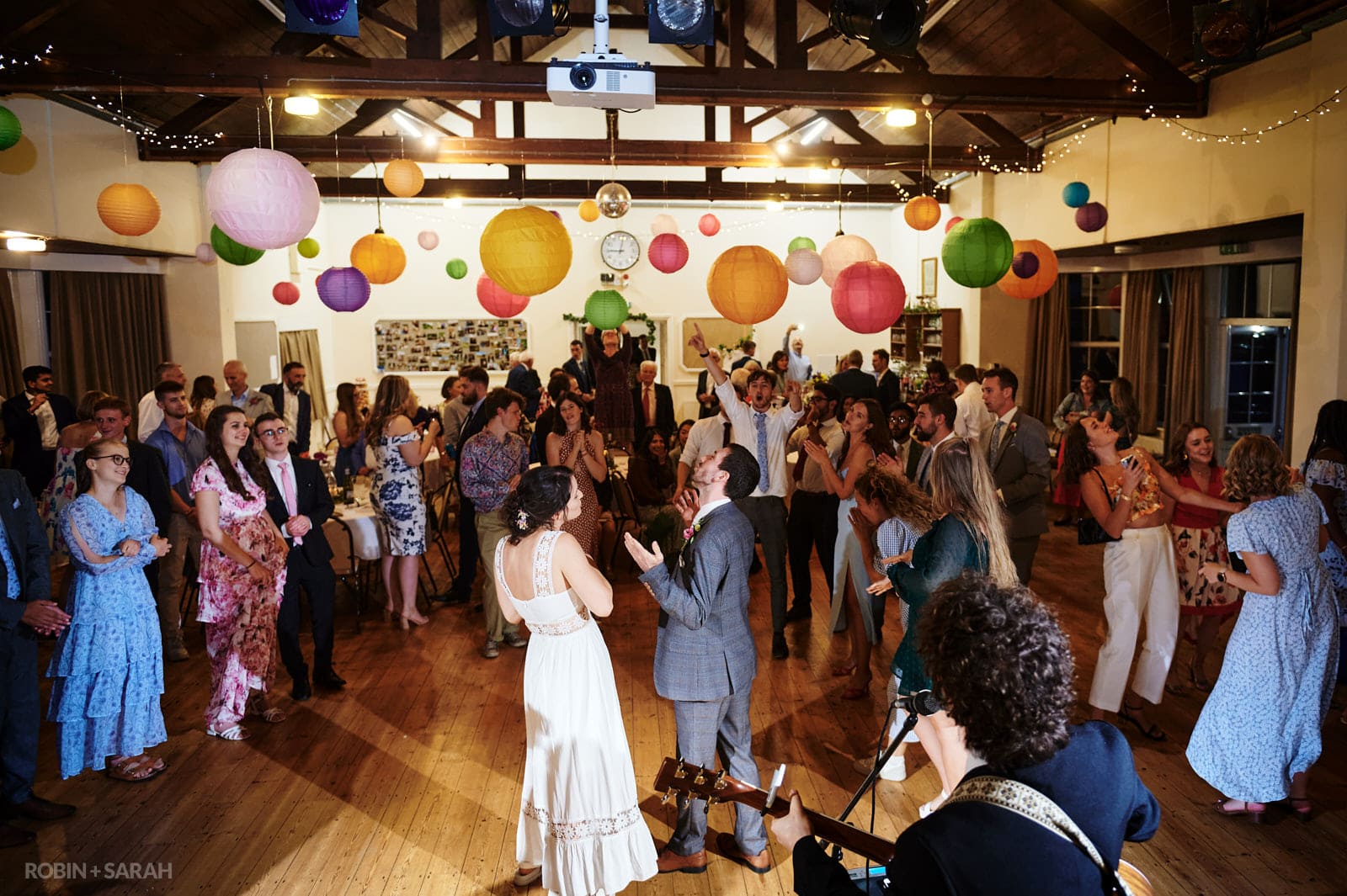 Bride, groom and wedding guests dancing in Dorothea Mitchell Hall in Warwickshire