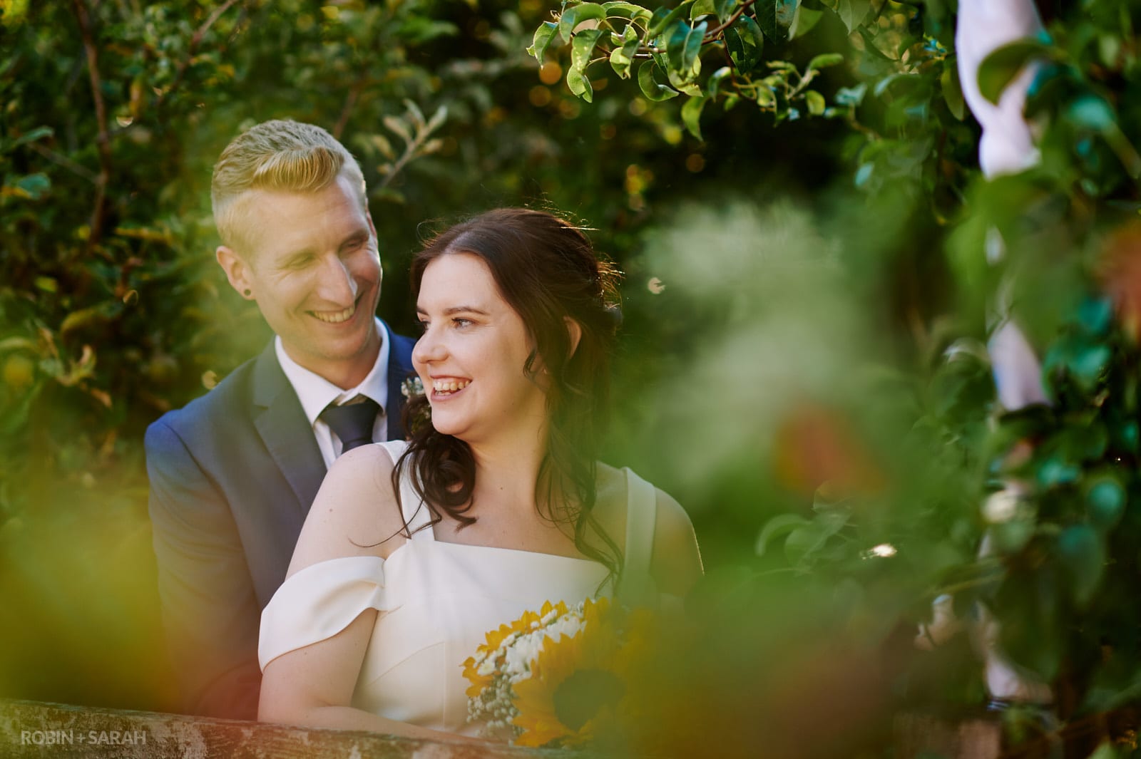 Bride and groom surrounded by trees in gardens at home