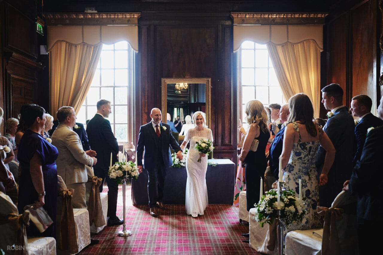Bride and groom exit wedding ceremony in Walnut Room at Coombe Abbey