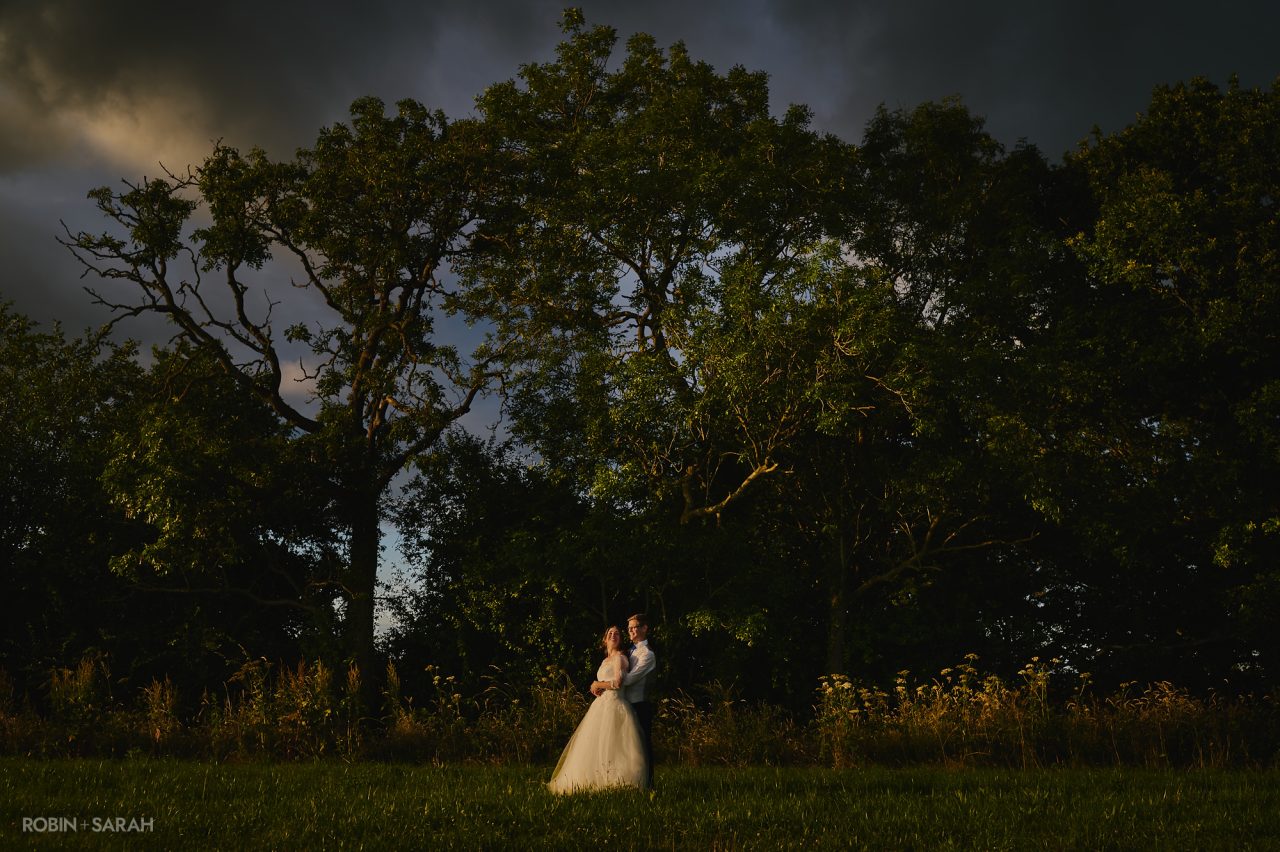 Couple in fields with the setting sun and dark sky