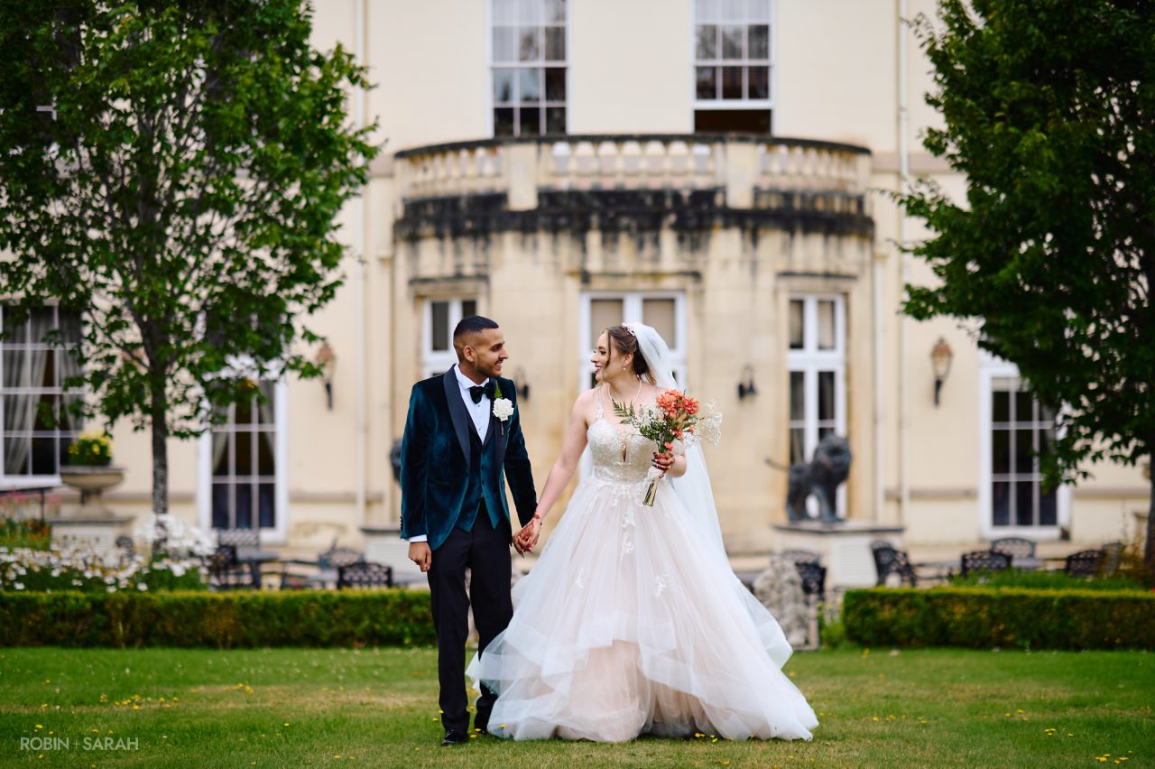 Bride and groom walking hand in hand in gardens at Spring Grove House in Worcestershire