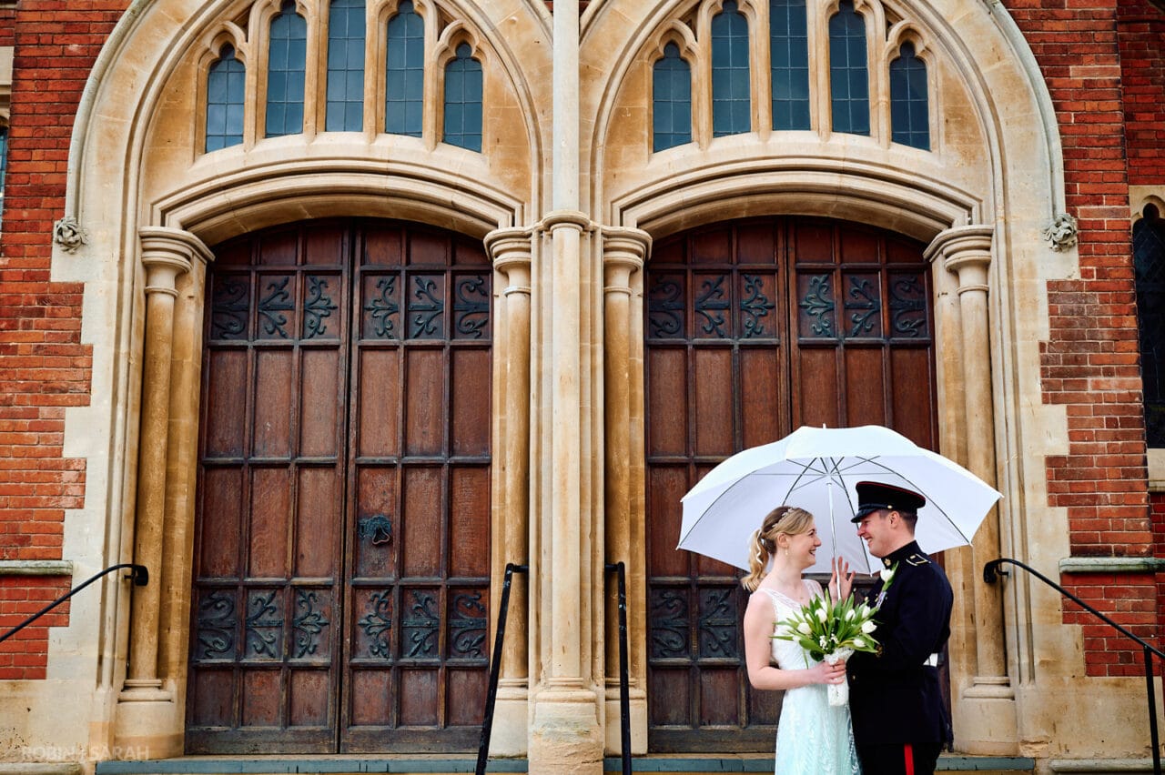 Bride and groom under umbrella in doorway of theatre