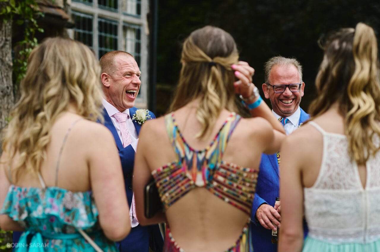 Groom and brother laughing with guests at wedding party