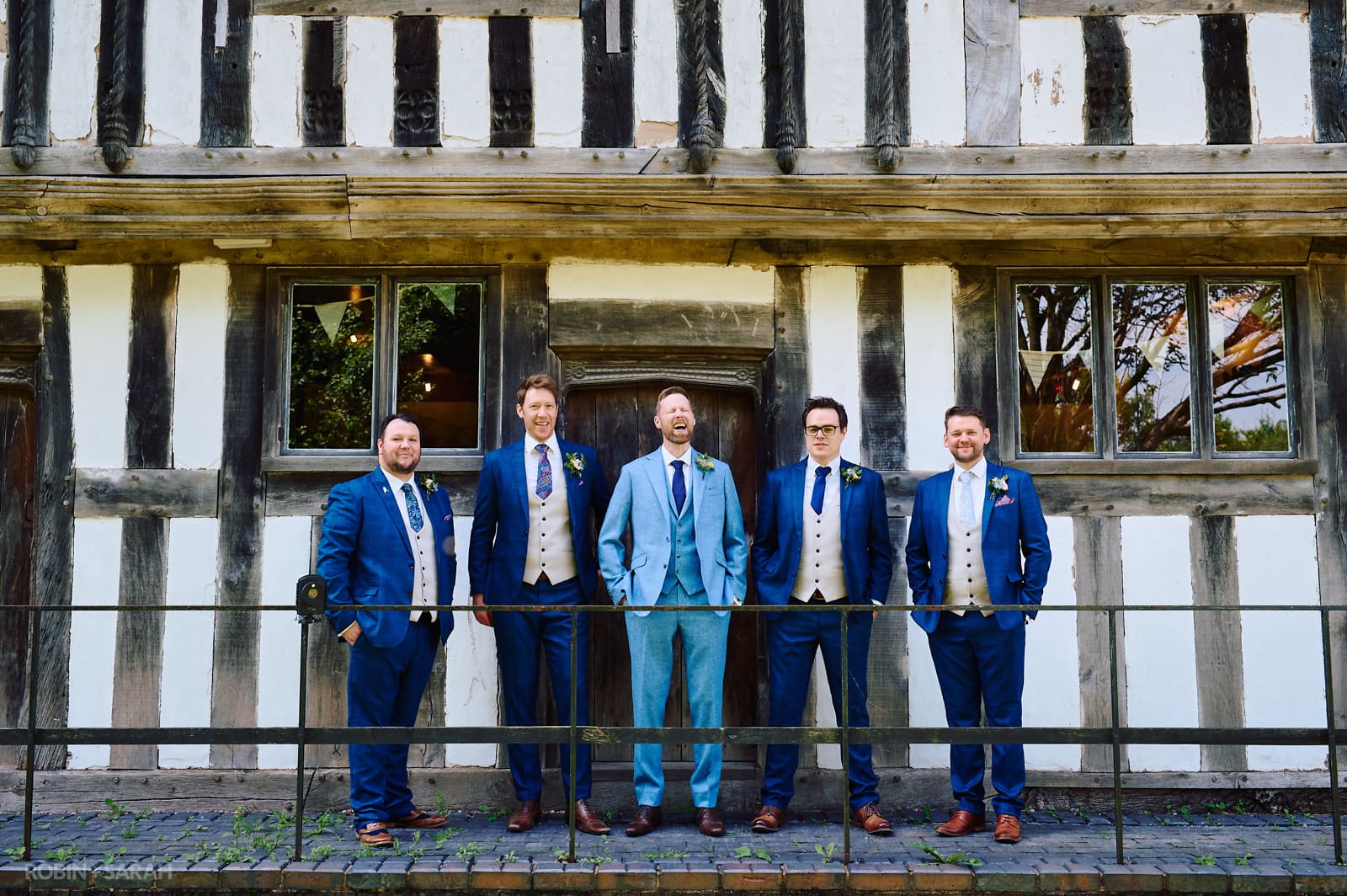 Groom and groomsmen laughing in front of old building